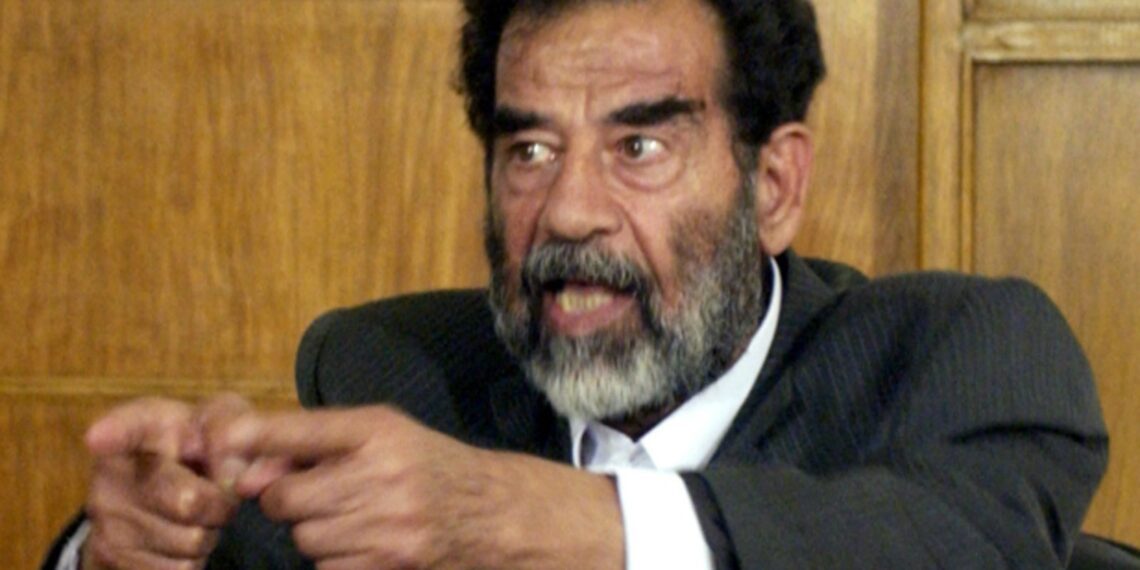 Saddam Hussein pointing both hands angrily during a speech or address.